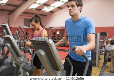 Woman and man stepping on step machines in gym