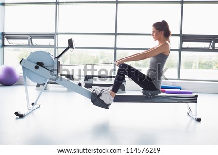 Woman working out on row machine in gym