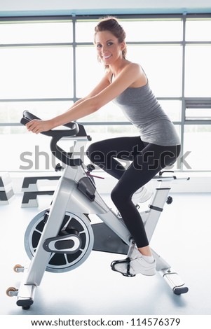 Smiling woman training on exercise bike in gym