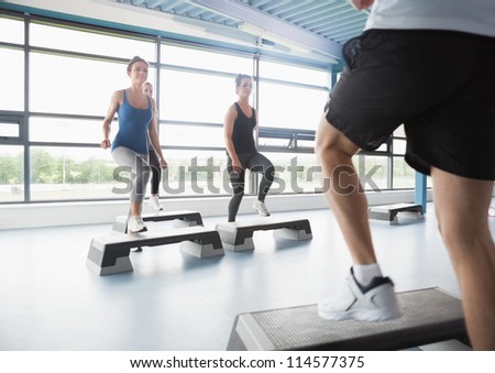 Trainer stepping with aerobic class in gym