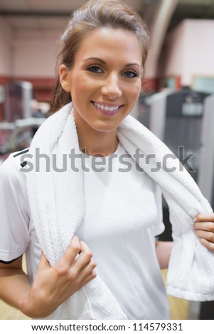 Smiling woman wearing a towel around her neck in gym