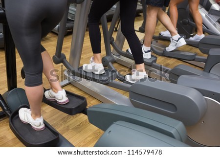 Four people stepping on step machine in gym