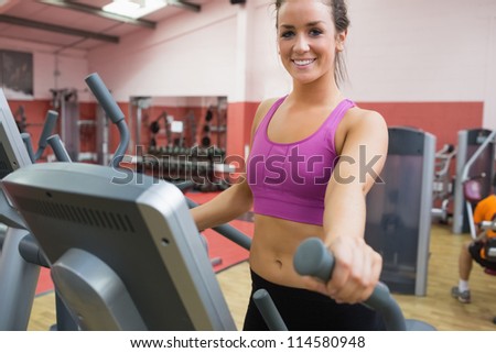 Smiling brunette stepping on a step machine in gym