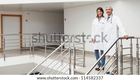 Two doctor standing at top of stairs in hospital