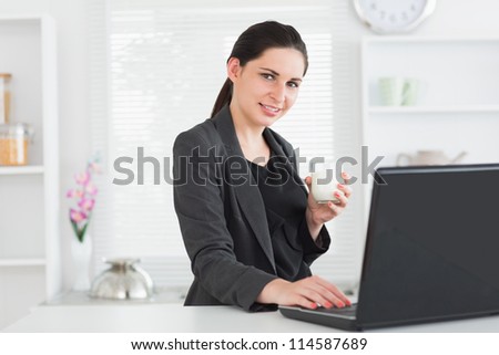 Smiling woman in front of laptop with glass of milk in lving room