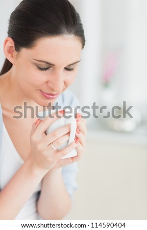 Woman with closed eyes holding a mug in a living room