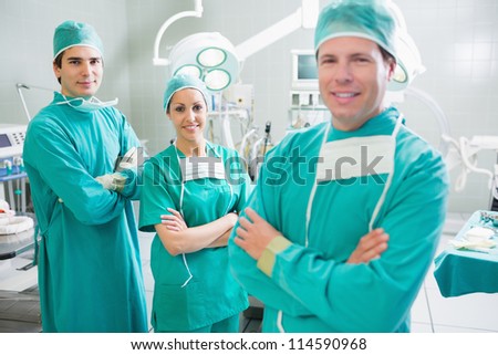 Smiling surgeons looking at camera with crossed arms in an operating theatre