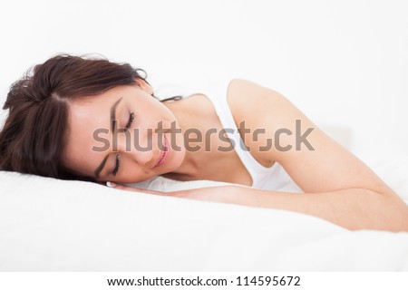Brunette woman falling asleep in her bed indoors