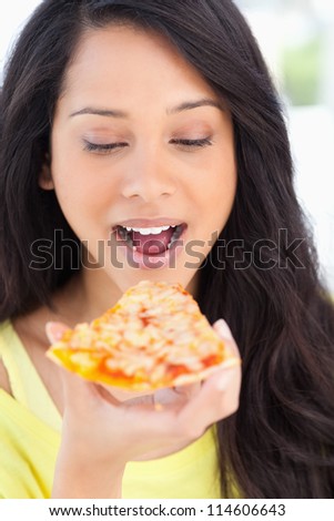 A close up shot of a woman with a pizza slice as she is about to eat it while looking at it