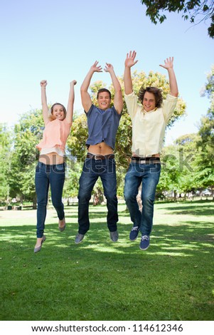 Three students jumping in a park