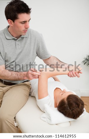 Osteopath stretching the arm of his patient in a medical room