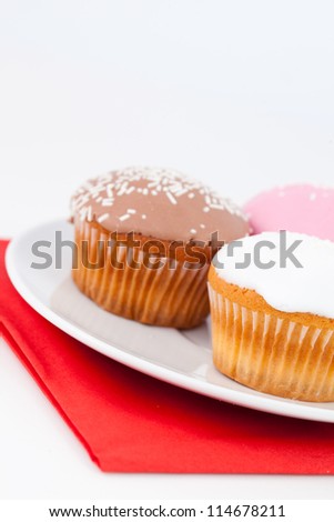 Three cupcakes on a white plate against a white baCKGROUND
