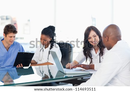 Smiling medical team working both on a laptop and a clipboard