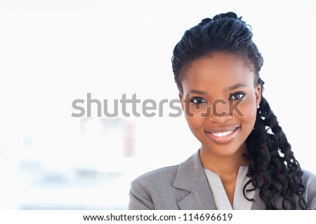 Smiling employee standing upright in front of a window while wearing a formal suit Smiling employee standing upright in front of a window while wearing a formal suit