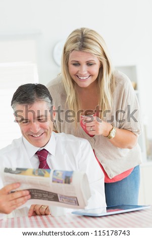 Couple reading a newspaper at the kitchen together before work