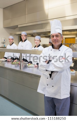 Head chef standing with arms crossed and team standing behind him