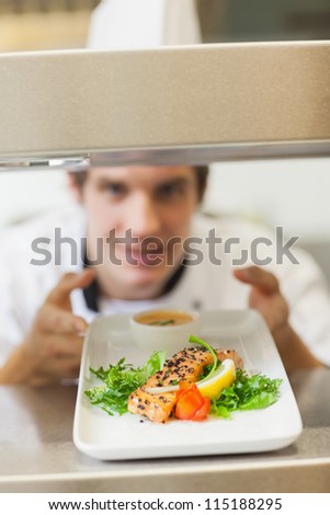 Chef handing salmon dinner through order station in the kitchen
