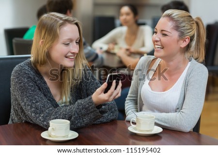 Women sitting at the coffee shop looking at the smartphone smiling