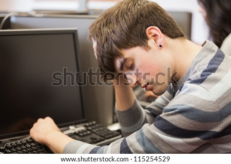 Student sitting sleeping at the computer desk in college