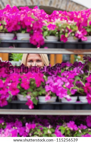 Woman looking through shelves in flowers store while smiling