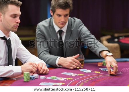Men placing bets at poker game in casino