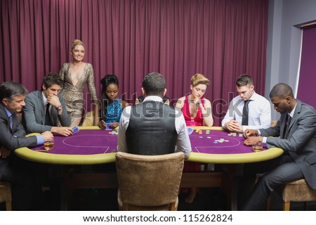 People sitting at the casino table with woman standing and smiling