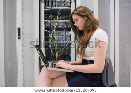 Female technician doing data storage with the laptop in data center