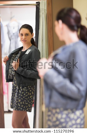 Woman trying on jacket and smiling in changing room