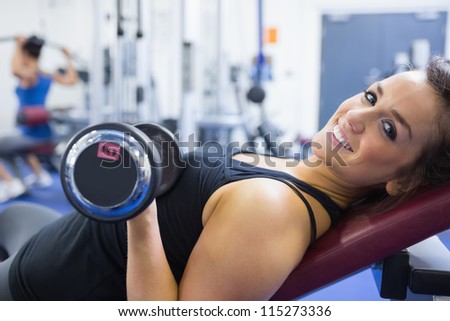 Smiling woman lifting weights in gym