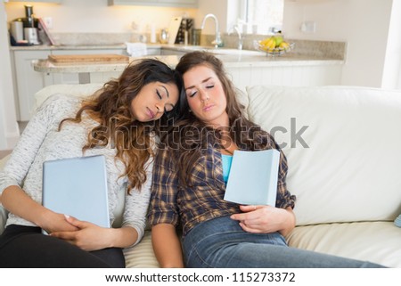 Women sleeping on a couch while holding tablet computers