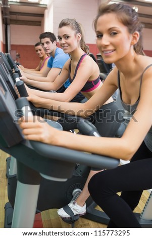 Three woman and one man on exercise bikes in gym