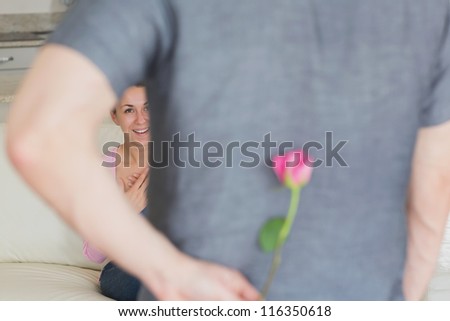Husband hiding flower behind back for wife in living room