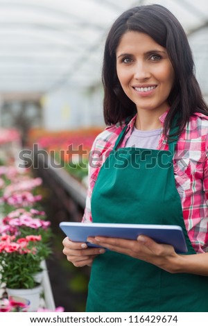 Woman doing inventory with laptop in working in greenhouse