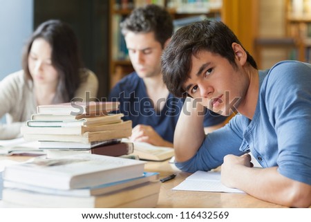 Student leaning on table looking tired at the library
