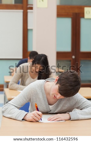 Man working hard on exam paper in exam hall