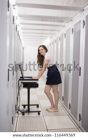 Smiling woman running diagnostics on servers in data center