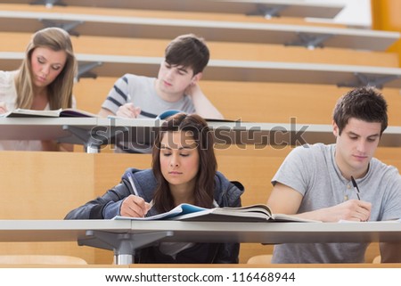 Students sitting at desks in lecture hall taking notes