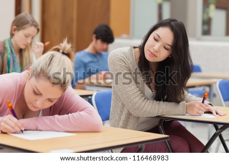 Girl copying another students work in exam i nexam hall in college