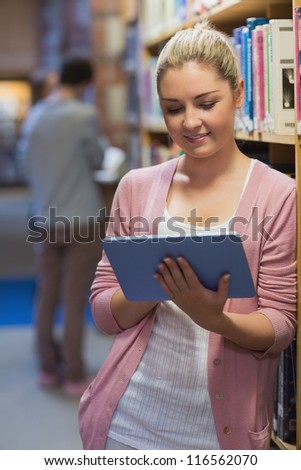 Woman using tablet pc in college library beside bookshelf