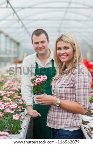 Woman choosing a flower in greenhouse with employee
