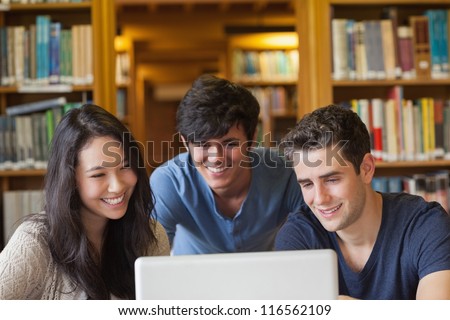 Students sitting looking at a laptop at the library