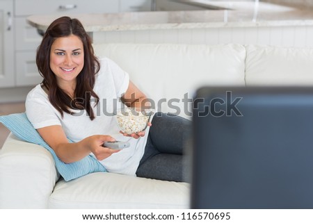 Brunette woman smiling and watching television