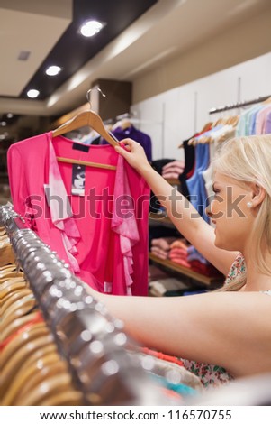 Woman is searching for clothes at a clothes rack in a boutique