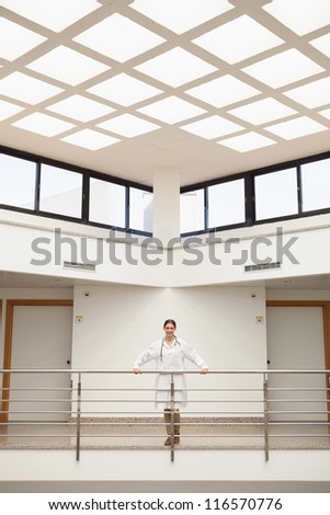 Female doctor leaning on the railing in hospital stairwell