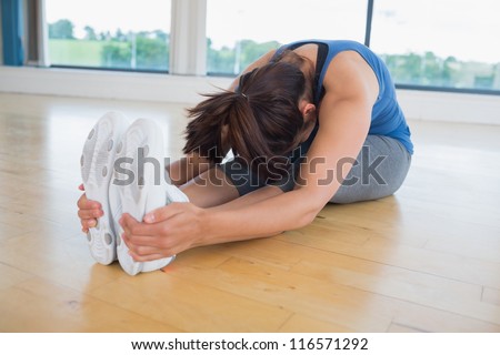 Woman in seated forward bend yoga pose in fitness studio