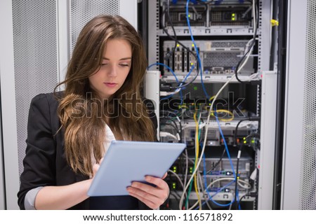 Woman using tablet pc in front of servers in data center