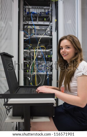 Happy woman running diagnostics on servers in data center