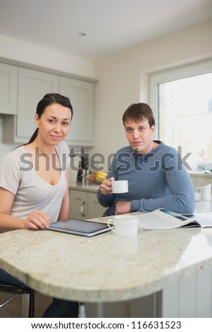 Two people sitting in the kitchen, drinking coffee and relaxing