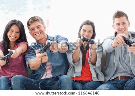 A happily smiling group of friends playing a game together while sitting on the couch
