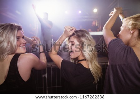 Happy female friends dancing at nightclub during music festival